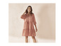 Une femme porte une robe rose avec des détails brodés.