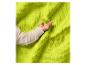 Main de bébé sur une couverture gaufrée douce vert lime.