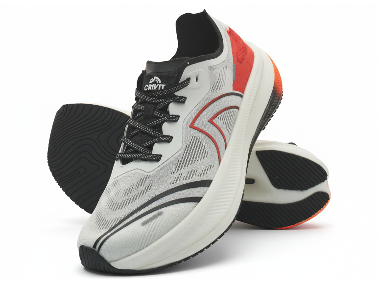 Paire de chaussures de sport blanches et rouges avec lacets et semelles noirs, l'une debout.