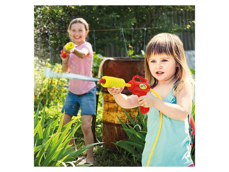 Des enfants jouent avec des pistolets à eau dans le jardin.