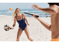 Femme en maillot de bain une pièce jouant au tennis de plage avec raquette et balle.