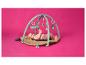 Bébé sur un tapis d'éveil avec des jouets suspendus sur un fond rose.