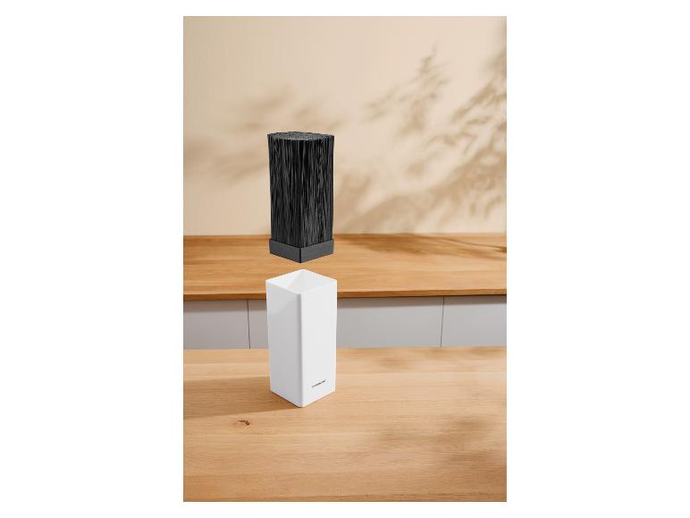 Un insert de bloc à couteaux noir flottant au-dessus d'un bloc à couteaux blanc sur un comptoir de cuisine en bois.