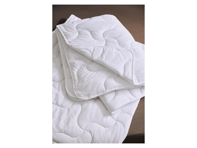 Couette ou couverture matelassée blanche pliée sur une surface marron