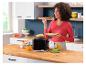 Femme prenant son petit-déjeuner avec un grille-pain, du pain, de la confiture, du café et du jus d'orange sur un comptoir en bois.