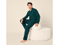 Homme en pyjama à carreaux verts assis sur un pouf blanc.