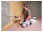Homme peignant un mur, éclairé par la lampe de travail LIVARNO® »The Painter«.