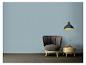 Fauteuil gris et table en bois avec vase sous une lampe noire sur un mur bleu.