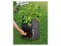 Une main prend des pommes de terre dans un sac de culture dans le jardin.