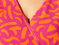 Gros plan sur une robe rose à imprimé orange.