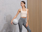 Une femme en tenue de sport tenant un ballon de fitness.