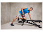 Homme faisant un exercice avec une kettlebell sur un banc réglable.