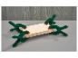 Planche en bois maintenue par quatre serre-joints à ressort verts sur une surface grise.