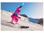 Enfant en combinaison de ski rose et gants de ski Crivit en train de skier.