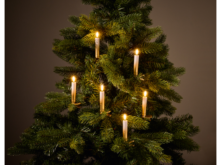 Sapin de Noël artificiel avec bougies LED allumées, sur fond sombre.