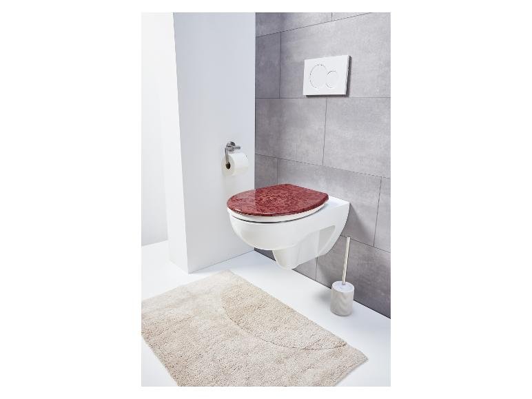 Toilette avec couvercle rouge et tapis.