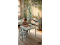 Chambre d'enfant avec papier peint forêt, lit cabane et enfant coloriant à une table avec chaise assortie.