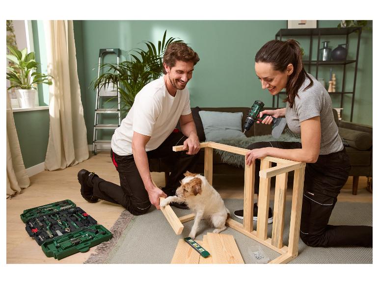 Un couple assemble des meubles avec des outils Parkside, tandis que leur chien regarde.