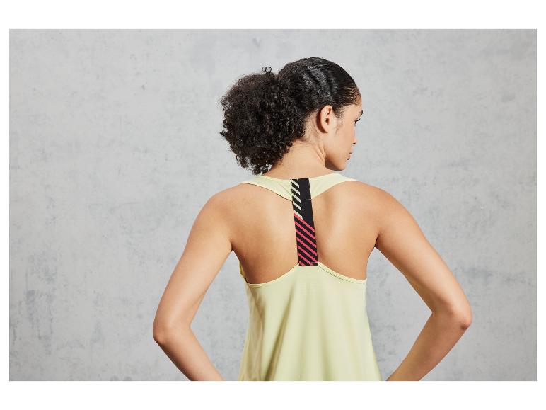Une femme porte un débardeur jaune clair avec un détail rayé dans le dos.