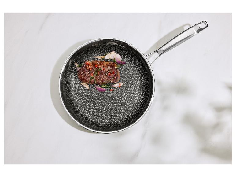 Poêle avec un steak cuit, du romarin et des échalotes sur une surface en marbre blanc.