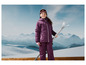 Une fille vêtue de vêtements de ski tenant des skis devant un paysage montagneux.