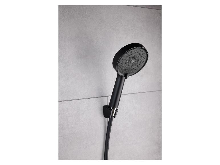 Une pomme de douche noire avec un long tuyau, fixée à un mur de carrelage gris.