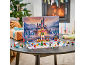 Calendrier de l'Avent pour enfants avec château miniature et figurines sur une table devant la cheminée.