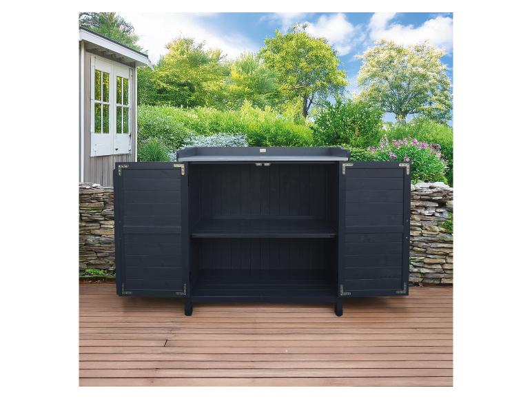 Armoire d'extérieur gris foncé avec portes ouvertes sur une terrasse en bois, entourée de verdure.