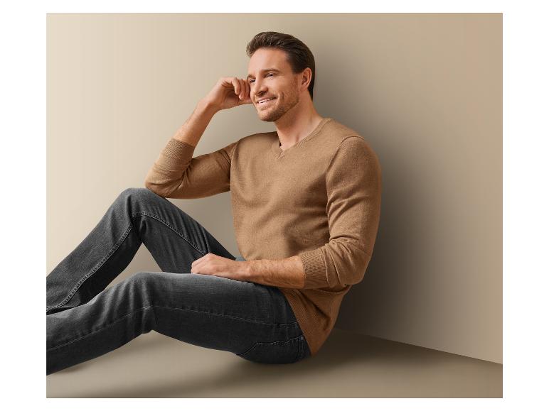 Un homme portant un pull marron et un jean bleu.