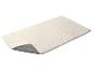 Un tapis rectangulaire blanc avec un envers antidérapant gris, partiellement plié.