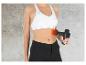 Une femme utilisant un pistolet de massage Vitalmaxx sur son abdomen.