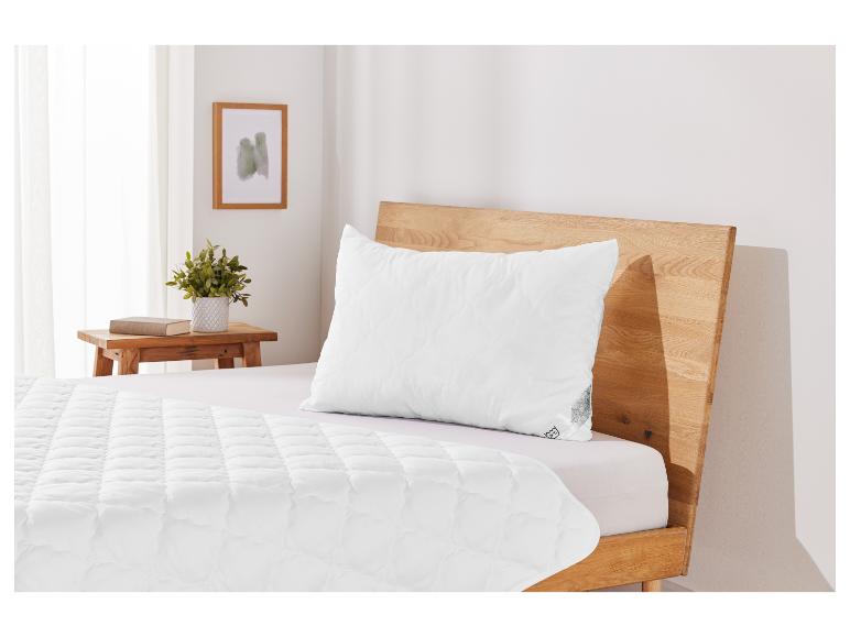 Un lit blanc avec une tête de lit en bois et une couette matelassée