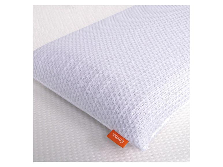 Oreiller blanc avec une surface texturée et une étiquette orange, posé sur un matelas blanc.