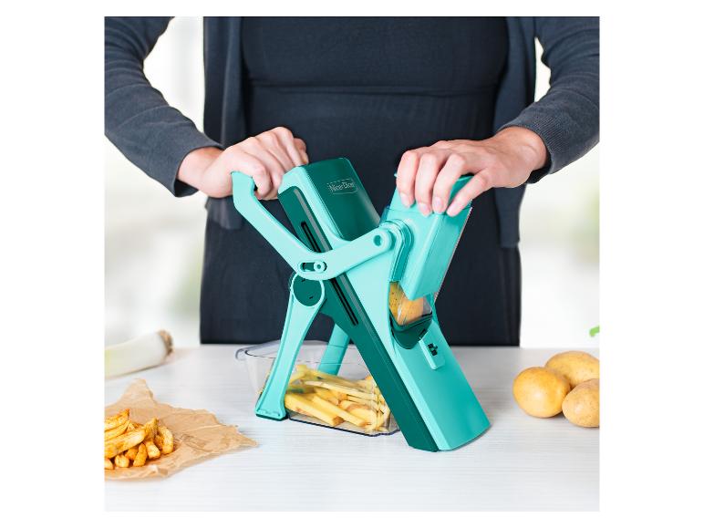 Femme utilisant un Nicer Dicer pour couper des pommes de terre dans la cuisine, avec des frites à proximité.