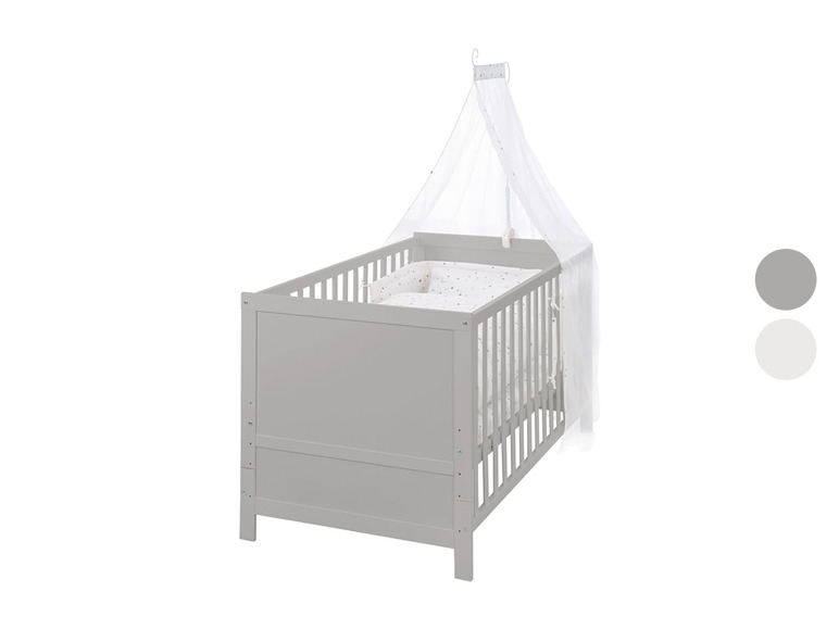 Un lit bébé gris avec un ciel de lit blanc.