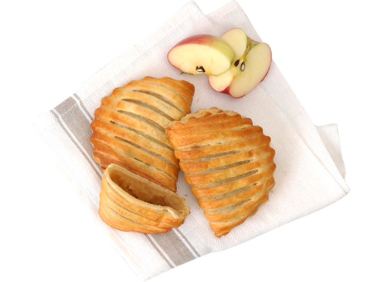 Trois chaussons aux pommes dorés et une pomme coupée sur un torchon blanc.
