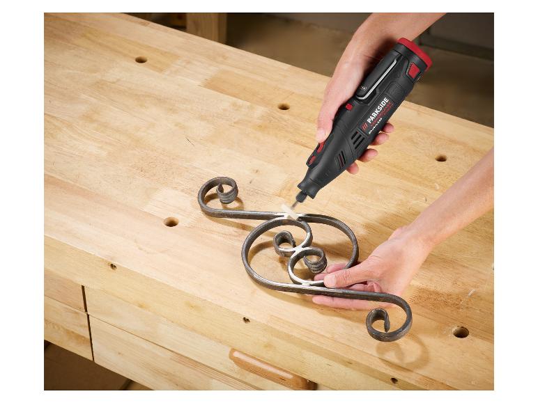 Une personne utilise un outil rotatif Parkside pour poncer un ornement métallique sur un établi.