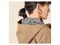 Femme en veste à capuche beige et chemisier à motifs noir et blanc, boucles d'oreilles dorées.