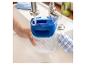 Une main remplit un récipient en plastique bleu avec de l'eau du robinet dans un évier.