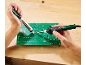 Mains soudant une carte de circuit imprimé avec un fer à souder et une pompe à dessouder