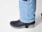 Une jambe de pantalon bleue avec des bottes en caoutchouc noires