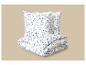 Parure de lit blanche à motif de feuilles bleues, pliée sur fond beige.
