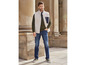 Un homme portant un gilet en polaire beige, un jean bleu et des baskets vertes.
