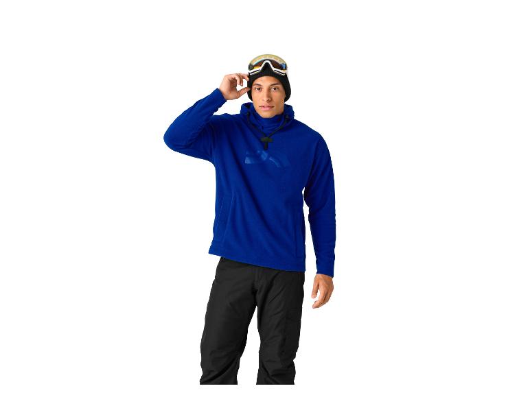 Homme en sweat à capuche bleu et pantalon noir, avec des lunettes de ski sur la tête.