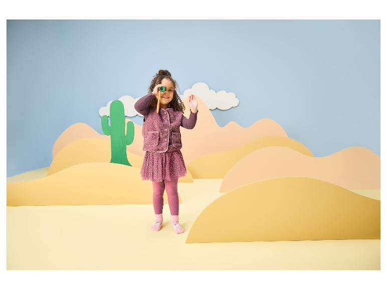 Fille en tenue violette avec des jumelles dans un décor de désert.