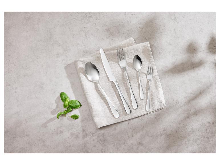 Couteaux, fourchettes et cuillères en acier inoxydable sur un tissu beige.