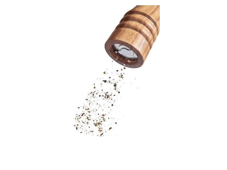 Moulin à poivre en bois répandant du poivre.