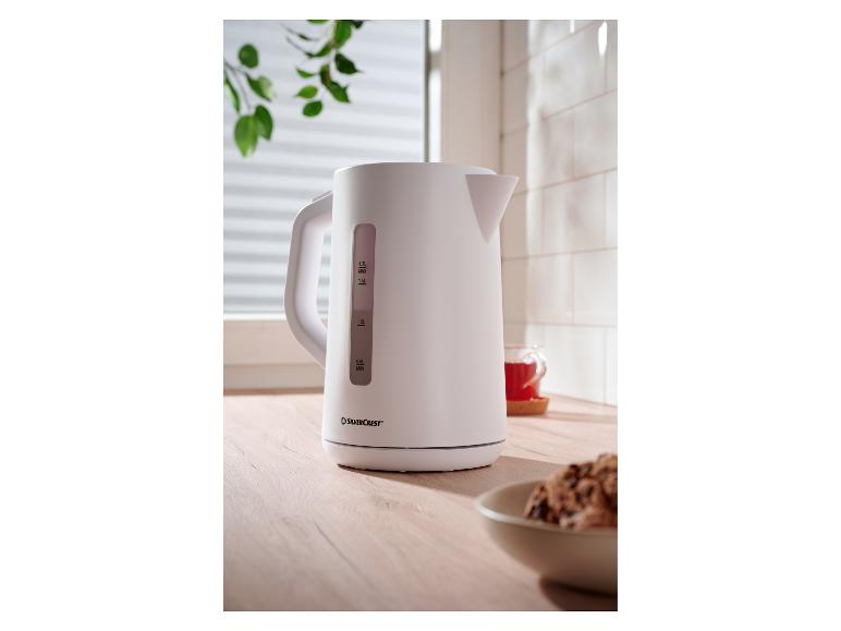 Bouilloire électrique blanche SilverCrest sur un comptoir en bois avec une tasse de thé.