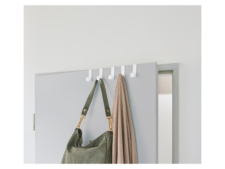 Crochets de porte blancs avec sac et cardigan suspendus sur une porte grise.