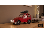 Voiture jouet rouge avec Père Noël et sapin de Noël sur une étagère en bois.